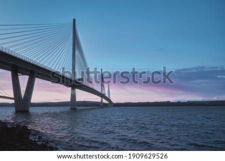 A view of a large three-tower cable-stayed bridge at sunrise. Queensferry Crossing Bridge, Scotland, United Kingdom Royalty-Free Stock Photo #1909629526