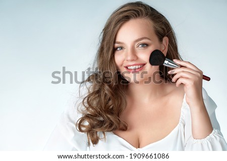 Woman with makeup brush. Photo of woman with perfect makeup on light blue background. Beauty and Skin care concept. Plus size model.