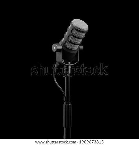 Podcast microphone on a tripod, a black metal dynamic microphone on an isolated black background, for recording podcast or radio program, show, sound and audio equipment, technology, product photo, dj Royalty-Free Stock Photo #1909673815