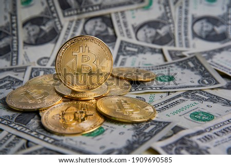 Pile of American one dollar cash. Next to it are several gold bitcoin digital cryptocurrency coins. Bank image and photo background.