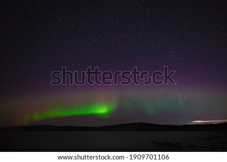 View of the aurora borealis. Polar lights in the night starry sky over the lake.