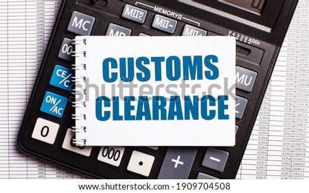 On the table are reports, a calculator and a card with the words CUSTOMS CLEARANCE on it. Business concept