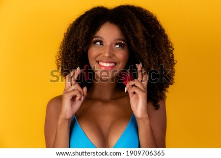 afro woman with fingers crossed cheering victory