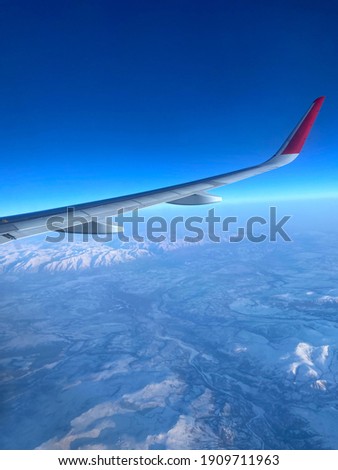 Airplane wing against the background of high mountains