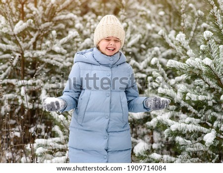laughing little girl playing with snow in beautiful winter forest. Child in warm clothes. Walking and active rest in winter forest
