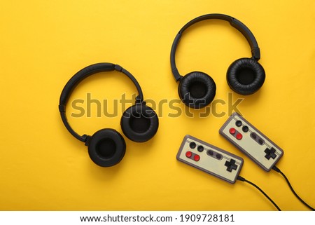 Stereo headphones with retro gamepads on yellow background. Time to play. Video game. Gaming concept