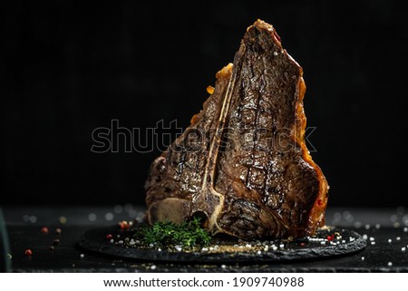 Aged Barbecue Porterhouse Steak. Beef T-Bone juicy steak rare beef with spices on a black table, banner, catering menu recipe place for text. Royalty-Free Stock Photo #1909740988