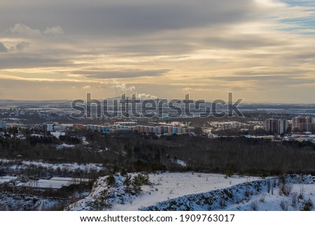 Winter view of the city of Brno in the Czech Republic in Europe. Houses and chimneys are visible. Palava can be seen in the background. There are dramatic clouds in the sky. Photo from Hady quarry.