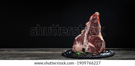raw porterhouse steak or Fed T Bone Steak dry aged of beef Ready to Cook on wooden Board with herbs, pepper and salt. Royalty-Free Stock Photo #1909766227