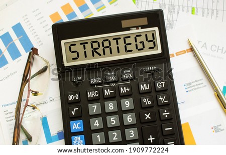 A calculator labeled STRATEGY lies on financial documents in the office. Business concept.