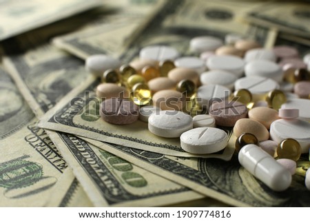 Lots of pills on the background of lots of hundred dollar bills