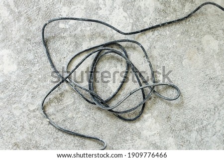Dirty dusty electric cable (extension cord) on the grunge rough floor in a renovated room in new apartment or home Royalty-Free Stock Photo #1909776466