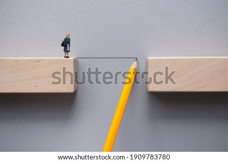 Pencil sketch bridging the gap between wooden blocks for female miniature figure to cross  Royalty-Free Stock Photo #1909783780