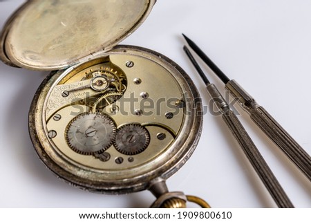 Antiques, vintage swiss pocket watch, two screwdrivers and tweezers lie on a white plastic table