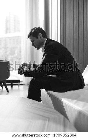 Young attractive male freelancer standing in hotel lobby. Working. Business lifestyle. Money. Success. Self-employed. Passive income. Remote work. Investment and finance. Boss. Black and white picture