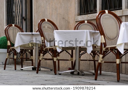 Empty restaurant tables with white tablecloths are waiting for customers.