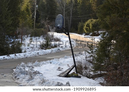 Basket Ball hoop in the snow on the side of a road