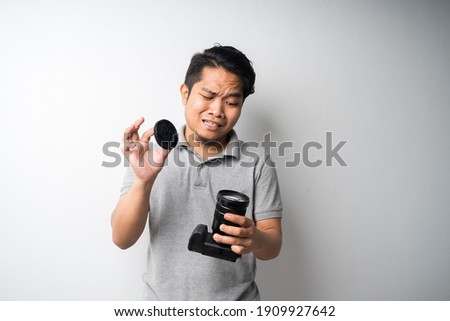 Young Asian man face expression with dslr or mirrorless camera. Photography, creative industry. Isolated selective focus.
