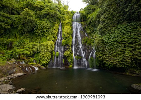 Waterfall with huge pond for swimming. Tropical landscape. Nature background. Travel adventure concept. Environment concept. Slow shutter speed, motion photography. Banyumala waterfall, Bali Indonesia