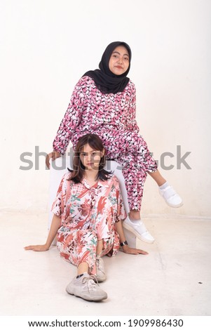 Two young sisters posing in pajamas on white background.