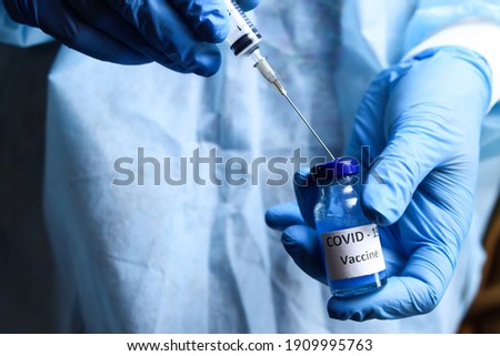 coronavirus vaccine and a syringe in the hands of a doctor or nurse. The concept of the fight against covid Royalty-Free Stock Photo #1909995763