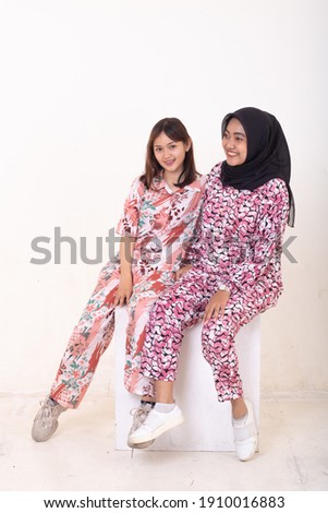 Two young sisters posing in pajamas on white background.