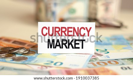 Finance and economics concept. On the table are bills, a bundle of dollars and a sign on which it is written - CURRENCY MARKET