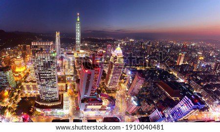 Aerial skyline of Downtown Taipei at dusk, vibrant capital city of Taiwan, with 101 Tower standing out among modern skyscrapers in Xinyi Commercial District and city lights dazzling under twilight sky