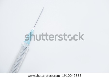 Crop one single syringe with dose of medicine or vaccine on white or gray background with a place for the text: vaccinations against influenza coronavirus, side view, soft focus, selective focus