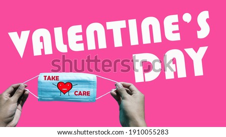 Valentine`s day, a mask with the words `take care` cartoon drawing of red love shape held by a man`s hand on isolated pink background.