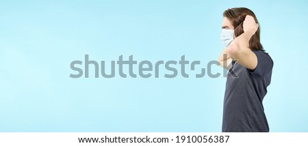 Portrait of a guy wearing a cloth mask on his face for security against viruses on an isolated light blue background, stay at home code-19 self-isolation. Panoramic banner background with copy space.