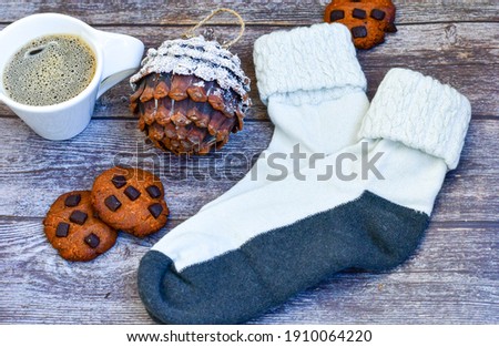 Cup  of   coffee,  peanut cookies ,warm scarf and white  socks  and pine cones on    wooden background . Winter lifestyle 