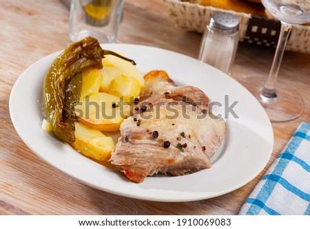 Close up of tasty baked pork with potatoes and baked green pepper, served on plate