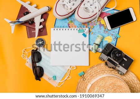 Open notebook with space for text on travel accessories on a yellow background. Planning your summer vacation, travel, and vacation. A set for a blogger, a traveler.