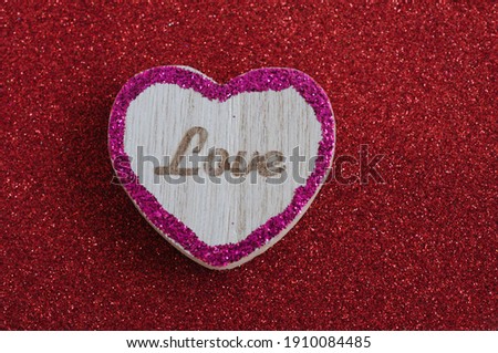 Brown love word on heart shaped wood with pink border on red background