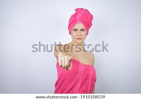 Young beautiful woman wearing shower towel after bath standing over isolated white background pointing with finger to the camera and to you, confident gesture looking serious