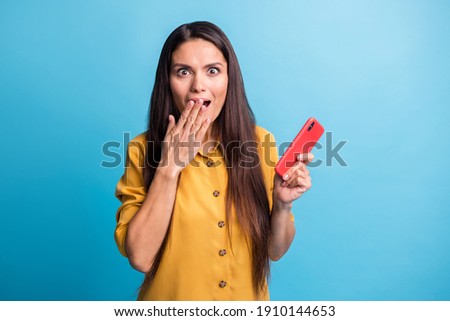 Photo portrait of amazed woman keeping mobile phone staring isolated on vivid blue color background