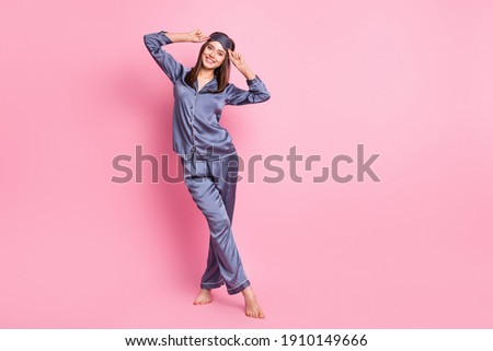 Photo portrait full body view of girl with crossed legs next to blank space touching eye mask isolated on pastel pink colored background