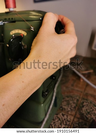 A woman sews her own bag on a green old vintage sewing machine.