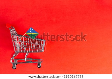 Shopping cart and Solomon islands flag on red background. Shopping online or eCommerce, delivery service store