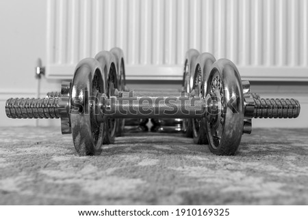 Black and white photo of a row of dumbbells on the floor at home
