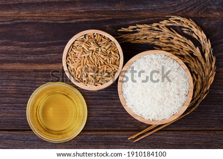 Rice bran oil extract with paddy and white jasmine rice isolated on wooden table background. Top view. Flat lay. Royalty-Free Stock Photo #1910184100