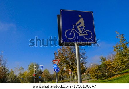 bicycle lane sign close-up across other road signs, trees and blue sky. Transportation. cycling