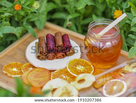 
honey jar, fruit marshmallow on a platter, tangerines, fruit orange, persimmon and apple frips on a tray in calendula flowers
