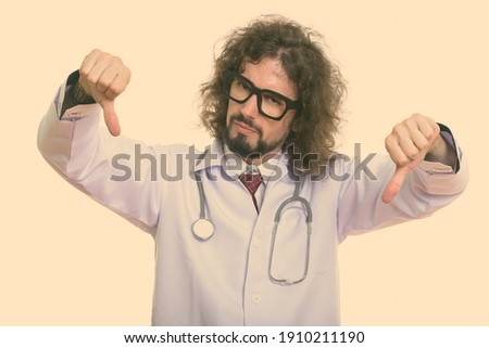 Studio shot of disappointed man doctor giving thumbs down