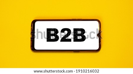 B2B on a smartphone with a yellow background. White screen phone with business word.