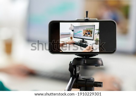 technology, post production and vlog concept - smartphone recording process of woman working in video editor program on laptop computer at home office