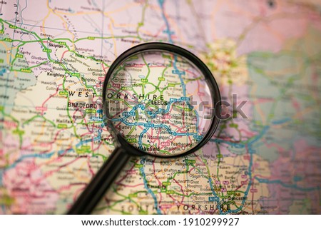 Close-up map of Leeds through black magnifying glass, city in England, United Kingdom