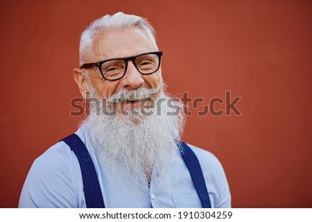 Cheerful hipster man in welcoming mood posing on red wall background - Fashionable person in casual fashion clothes - Happy elderly lifestyle concept with no age limit