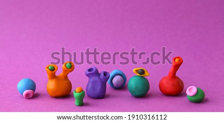 Handmade clay plasticine figurines on pink background. Colorful slugs from play dough. 